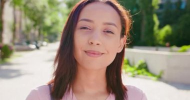 Açık havada gülümseyen esmer bayan.