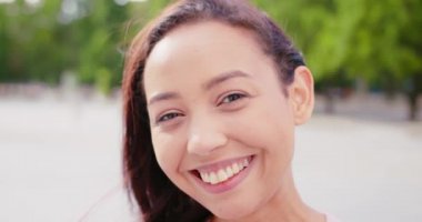 Açık havada gülümseyen esmer bayan.