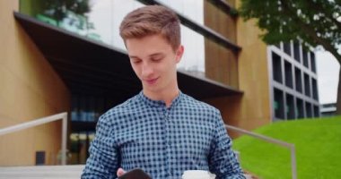 Genç adam dışarıda telefon kullanıyor.