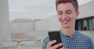 Genç adam dışarıda telefon kullanıyor.