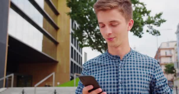 Молодой человек использует телефон на улице — стоковое видео