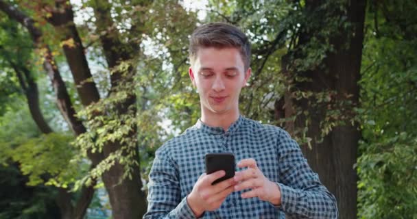 Joven usando un teléfono al aire libre — Vídeos de Stock