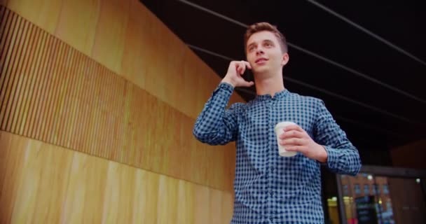 밖에서 전화를 사용하고 있는 젊은이 — 비디오