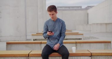 Genç adam dışarıda telefon kullanıyor.