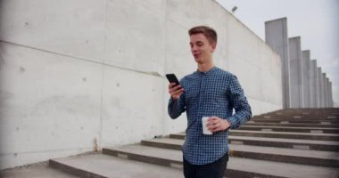 Genç adam dışarıda telefon kullanıyor.