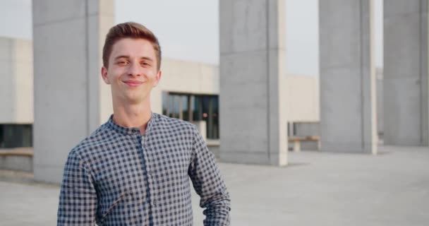 Fiatal jóképű férfi áll és mosolyog a szabadban — Stock videók