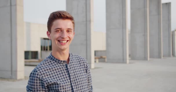 Jovem homem bonito de pé e sorrindo ao ar livre — Vídeo de Stock
