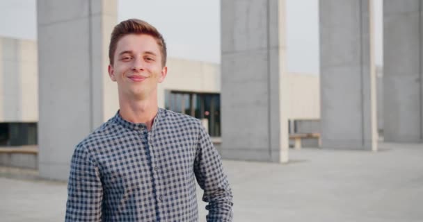 Joven hombre guapo de pie y sonriendo al aire libre — Vídeos de Stock