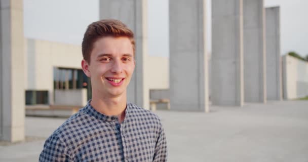 Fiatal jóképű férfi áll és mosolyog a szabadban — Stock videók