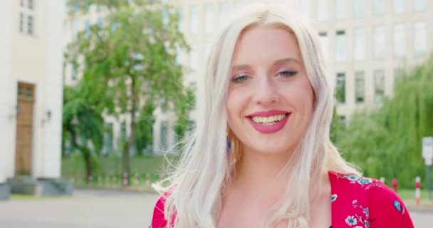 Молодая блондинка улыбается на улице — стоковое видео