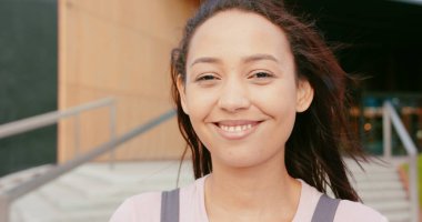 Açık havada gülümseyen esmer bayan.