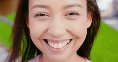 Açık havada gülümseyen esmer bayan.