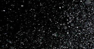 Havada süzülen beyaz kar taneleri bulutu. Parlak tanecikler, izole edilmiş siyah bir zemine doğru yavaşça düşüyor.