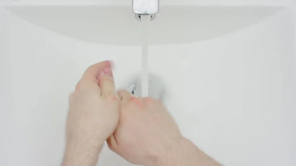 風呂場の洗面台で石鹸と水で手を徹底的に洗っている男のクローズアップ — ストック写真