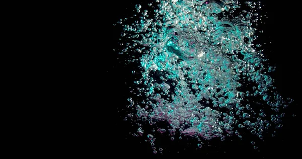stream of bubbles poring into a dark underwater background and changing from blue to pink.