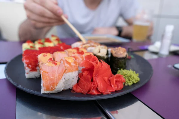 Primo piano del sushi. Il ragazzo mangia sushi e rotola con le bacchette — Foto Stock