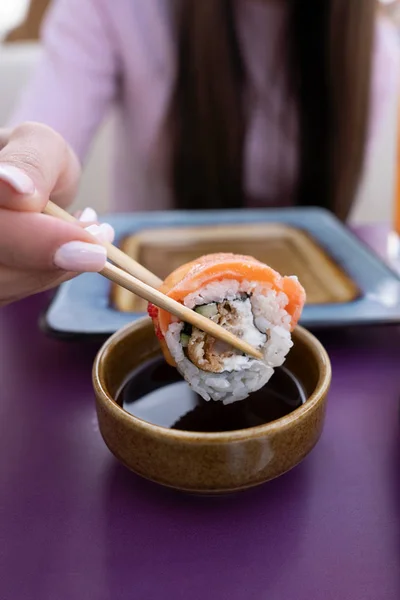 Sushi di dune di mano femminili in salsa di soia. La ragazza mangia sushi e rotola con le bacchette — Foto Stock