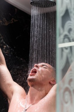 Adam duşta yıkanıyor. Karanlık duvarlarile Duş