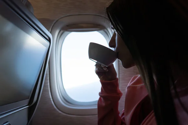 Jonge vrouw drinkt koffie in het vliegtuig — Stockfoto