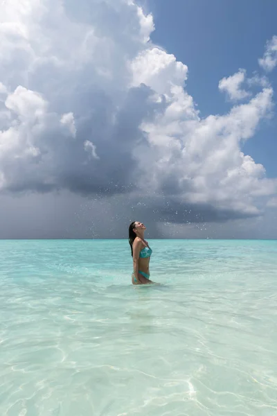 A young girl makes splashes when she drastically pulls her hair out of the water. Royalty Free Stock Images