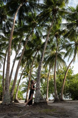 Genç bir kız hindistan cevizi ile uzun palmiye ağaçlarının altında yürüyor.