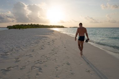 Güçlü adam ıssız bir sahilde gün batımına gider.