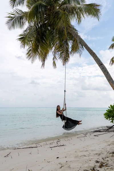 Salıncakta ata binen genç bir kız. Suyun üzerindeki palpe üzerinde asılı salıncak