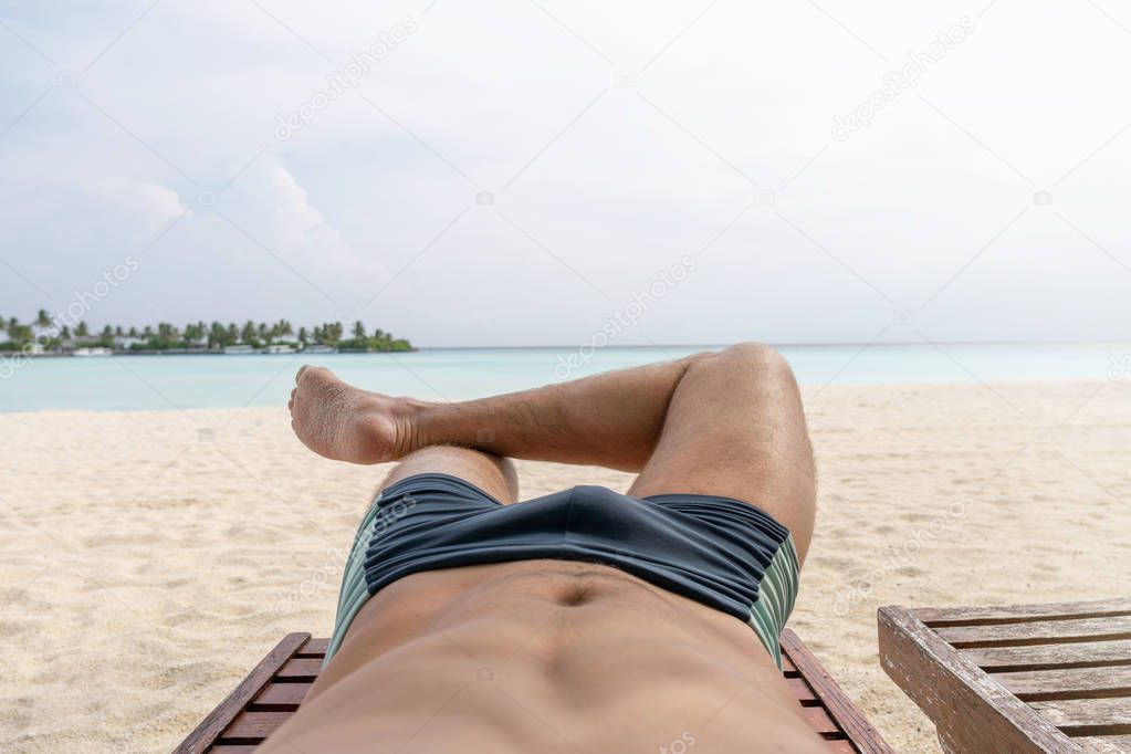 Relax on the beach. In the frame of the lower body of the guy.