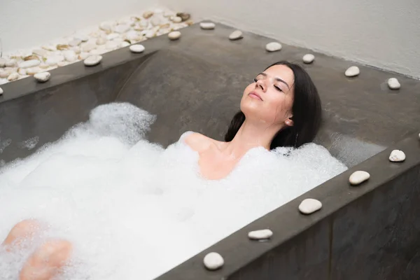 Un verdadero relax para una chica moderna. Hermosa morena toma un baño con espuma . — Foto de Stock