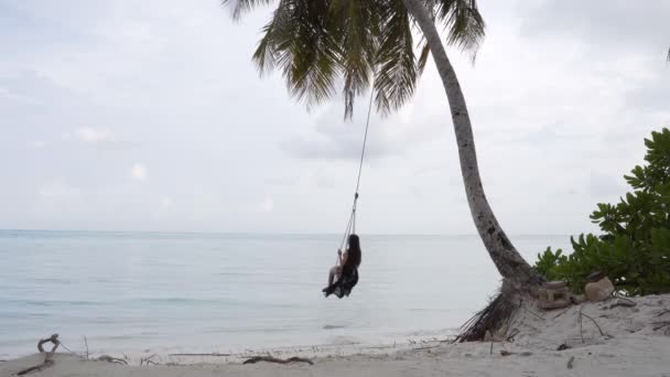 Uma rapariga a cavalgar num baloiço. Balanço suspenso no palpe acima da água — Vídeo de Stock