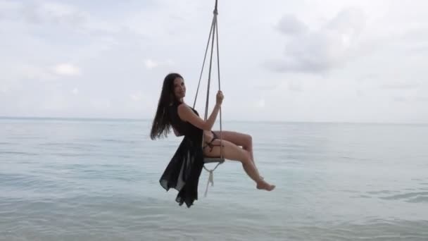 ブランコに乗っている若い女の子。水の上のパルプに吊り下げられたスイング — ストック動画