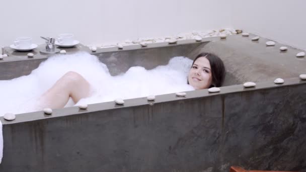 Μια πραγματική χαλάρωση για ένα μοντέρνο κορίτσι. Όμορφη μελαχρινή παίρνει ένα μπάνιο με αφρό. — Αρχείο Βίντεο