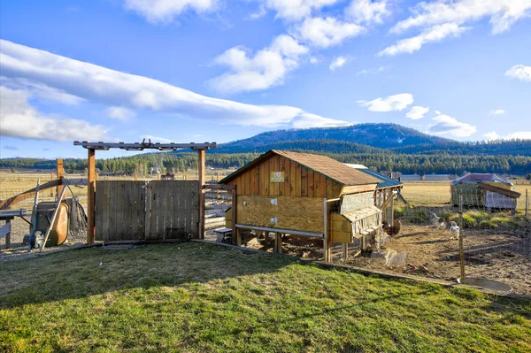 Small chicken coop in the back yard of a farm house with mountain landscape. Northwest, USA