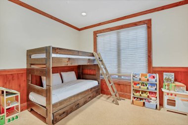 Ahşap bunkbeds, renkli plastik kutuları için oyuncaklar, ahşap panelli duvarları ve duvardan duvara halı odası ranza.