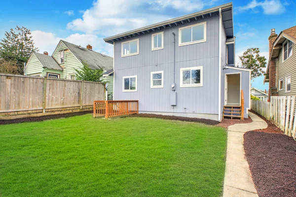 Blue home exterior with large fully fenced back yard and well kept lawn.