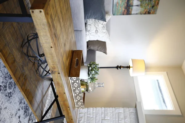 家庭房内有一个木和金属框架咖啡桌旁边的灰色沙发与枕头 — 图库照片
