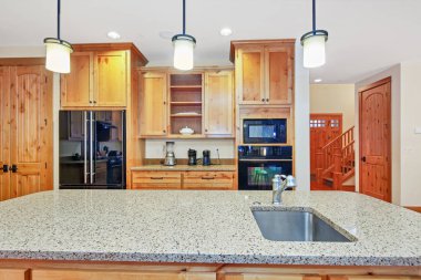 Hafif ahşap dolaplar, granit tezgahlar ve siyah aletleri ile güzel mutfak.