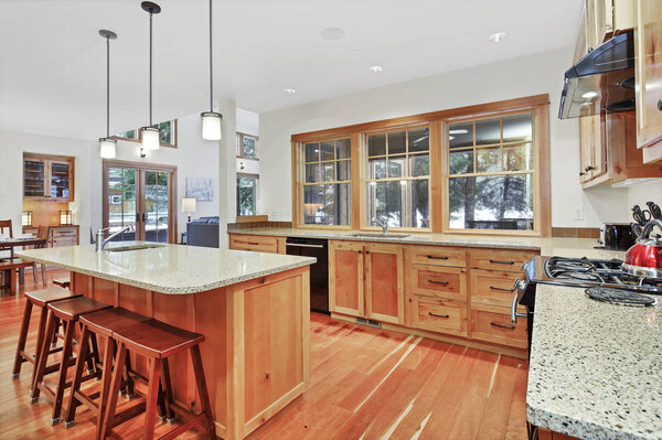 Кухня со светлыми деревянными шкафами, гранитными столешницами и кухонным островом барного стиля
.