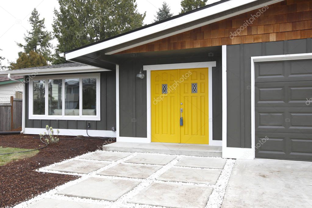 Home entrance with yellow front doors of a lovely gray house.