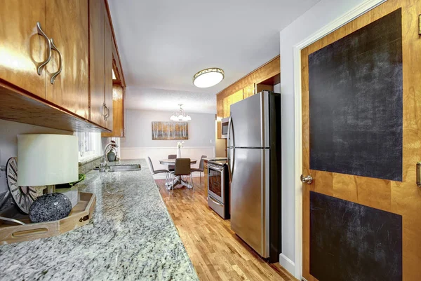 Natural wood cabinets in kitchen interior with island and black refrigerator.