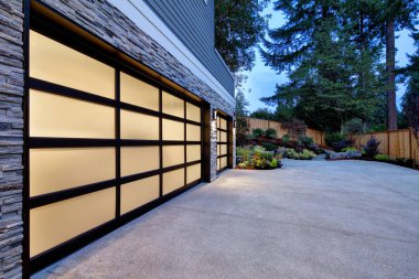 Modern ev dış iki araç garaj, alacakaranlıkta geniş driveway ile