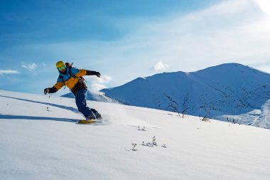 The guy is riding a snowboard. In the mountains in pristine snow. Mountains of Kyrgyzstan clipart