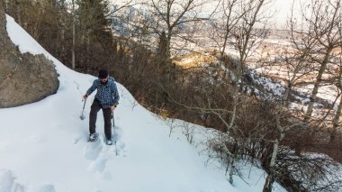 Hiker in the mountains walks on snowshoes. A man rises to the top. Winter mountain tourism. Kazakhstan