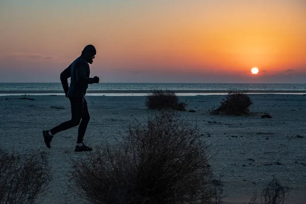 A man engaged in running. The athlete runs along the seashore at sunset. Trail running. Mangystau Peninsula