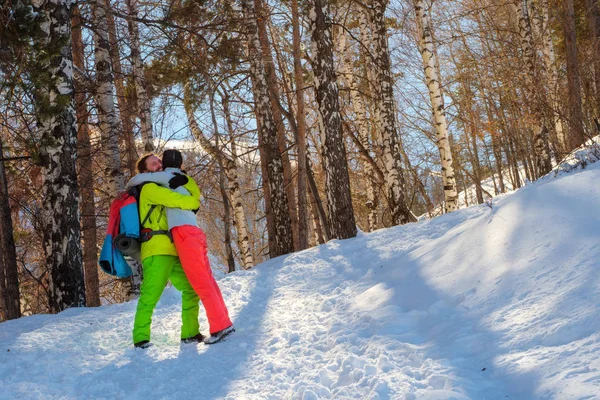 El tipo con la chica está caminando en el bosque de invierno. Día soleado en las montañas —  Fotos de Stock