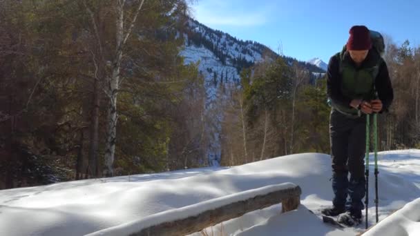 游客在山上穿着雪鞋散步 他坐在木长凳上休息 山中阳光明媚的日子 — 图库视频影像