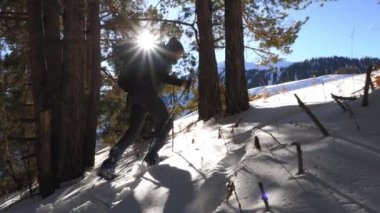 Adam kışın kar ayakkabıları üzerinde yokuş yukarı tırmanıyor