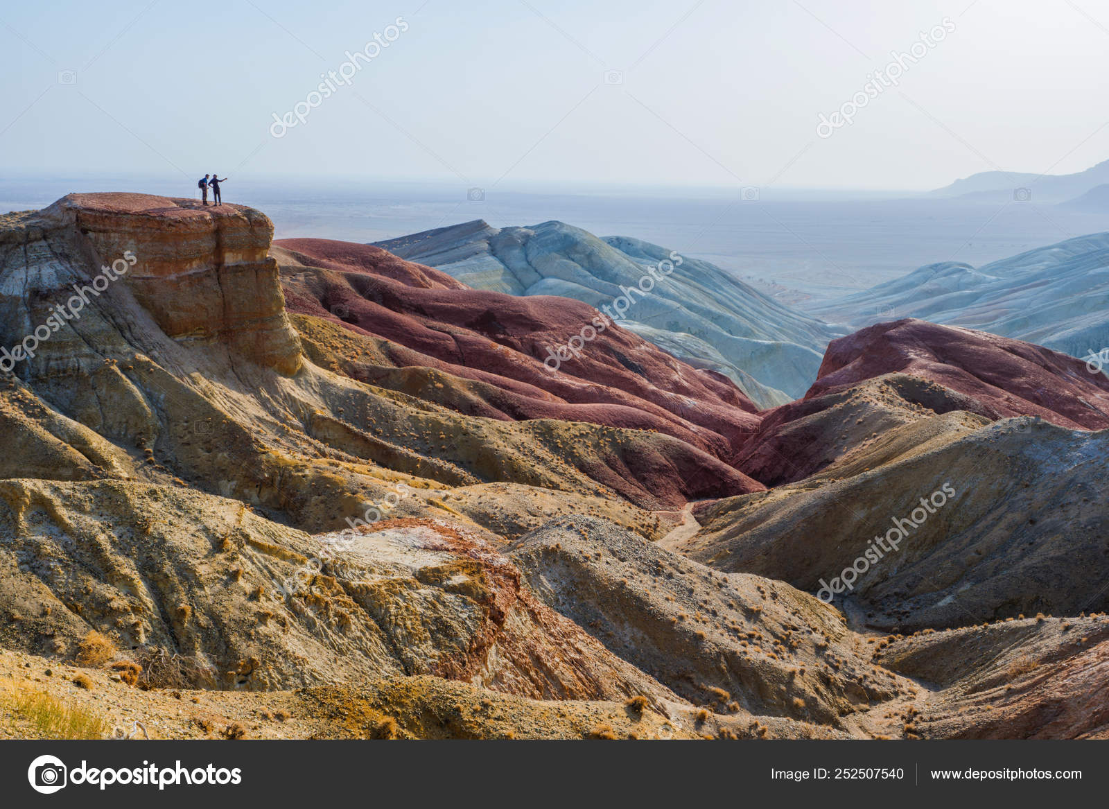 Travelers stand on the edge of a cliff against the backdrop of an epic ...