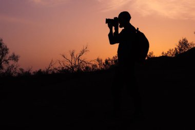 Bir sakallı fotoğrafçı alarak fotoğraf günbatımı ışık siluet.