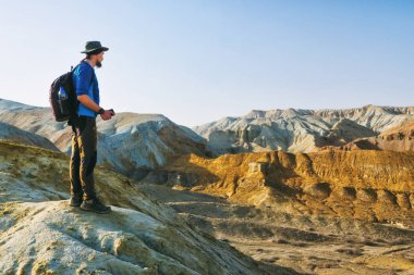 Gezgin adam bir çöl Dağ manzarası arka plan üzerinde bir tepenin kenarında duruyor